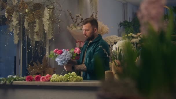 集中花屋は花店で花束に複数の色の花を追加します 男性労働者は美しい花の束を収集します 植物がたくさんある部屋 小売業の花ビジネスと起業家精神 — ストック動画