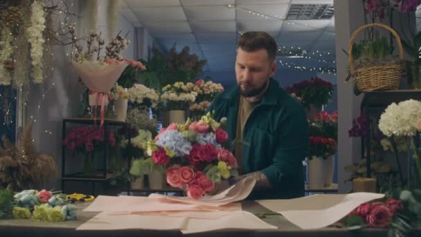 Профессиональный Флорист Заворачивает Красивый Букет Оберточной Бумагой Коллега Вазой Цветов — стоковое видео