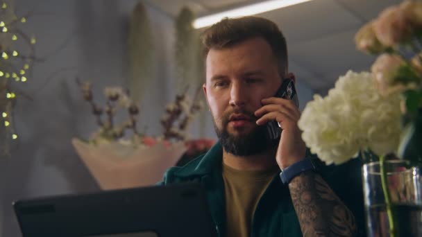 Erkek Girişimci Çiçekçide Çiçekçi Müşteriyle Telefonla Konuşur Dijital Tablet Kullanarak — Stok video