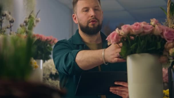 男性花屋は花瓶に花をカウントし デジタルタブレットコンピュータを使用してオンライン注文を取ります 小さなビジネス起業家 花屋のオーナー 花ビジネスと起業家精神の概念 — ストック動画