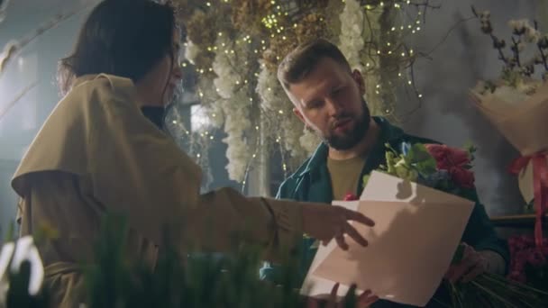 Mannelijke Bloemist Verzamelt Bloemen Aan Vrouwelijke Klant Versiert Met Inpakpapier — Stockvideo