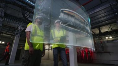İstasyonda sanal rüzgar türbini ve 3 boyutlu hologram kullanan elektrik hatlarının detaylarını izleyen iki erkek çalışan. Modern ve dijital elektrik üretim sistemi. Yeşil ve yenilenebilir enerji.