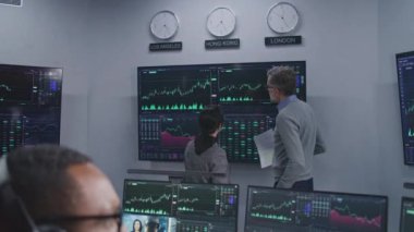 Mali analistlerden oluşan ekip, birçok büyük ekranda döviz piyasası grafiklerini analiz ediyor. Gerçek zamanlı sergilenen hisse senetleriyle bilgisayar başında çalışan Afro-Amerikan bir adamı vurdu. Ticaret ve yatırım..