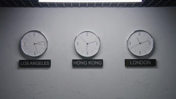 モダンなデザインのオフィスでLedランプによって照らされたウォーキングウォールクロック 時計の下に書かれた大都市の名前 ランニングタイムポインタを持つ時計は 異なる都市のタイムゾーンを示しています ズームイン — ストック動画