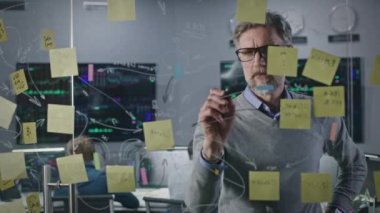 Olgun yatırım bankacısı, simsar bürosundaki yapışkan notlarla cam duvara resim çiziyor. İşadamı şirketin iş stratejisini geliştirir ve analiz eder. Meslektaşlar gerçek zamanlı hisse senetleriyle bilgisayarlar üzerinde çalışırlar.