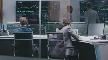 Çeşitli finansal analistler bilgisayarlardaki gerçek zamanlı hisse senetlerini izliyor. İş adamlarından oluşan bir ekip banka ofisinde çalışıyor. Döviz piyasası grafiklerini gösteren büyük dijital ekranlar. Kripto para birimi ticareti ve analizi.