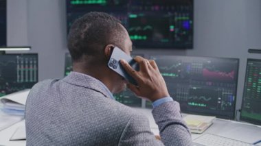 Afro-Amerikalı borsa simsarı telefonla konuşur, broker ofisinde çalışır. Bilgisayar monitörleri ve gerçek zamanlı hisse senetleri olan büyük ekran, borsa grafikleri. Yatırım, kripto para ticareti ve analitik.