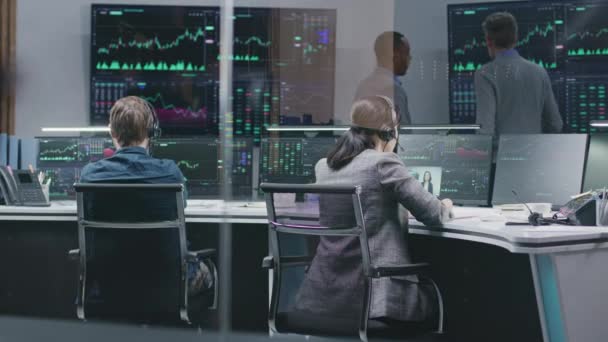 多様な金融アナリストは コンピュータ上のリアルタイム株式を監視します ビジネスマンのチームは銀行のオフィスで働いています 取引所市場チャートを示す大きなデジタル画面 暗号通貨取引と分析 — ストック動画