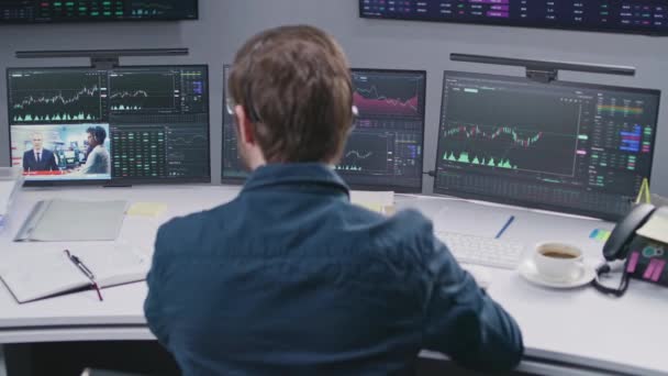 ヘッドセットの男性アナリストは ニュースを見て リアルタイム株式 取引所市場チャートや商品とマルチモニターコンピュータ上の銀行のオフィスで動作します 暗号通貨取引 投資と分析 — ストック動画