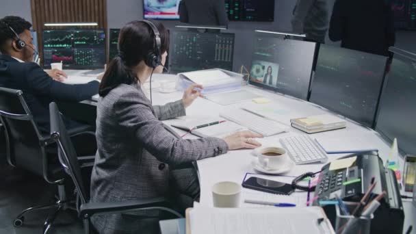 女交易者用记事本书写 并在计算机上使用显示的实时股票 同事们在大屏风的背景下分析外汇市场图表 加密货币交易和投资 — 图库视频影像