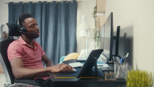 アフリカ系アメリカ人の男がコンピュータに座っている カメラの変更ビューは自宅でリモートで動作します 隣に住んでいる2人の同僚がオンライン会議で話しています 周辺の概念 — ストック動画