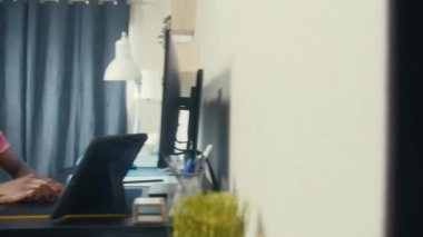 Afrikalı Amerikalı adam bilgisayarda online konferansta konuşuyor. Yan dairede yaşayan finansal analistin kamera görüntüsü değişiyor. Duvarla ayrılmış iki daire. Komşuluk kavramı.