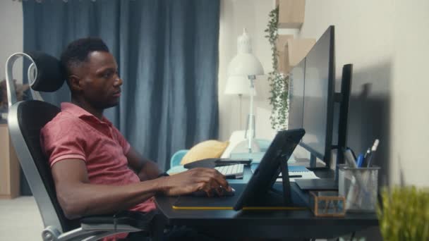 アフリカ系アメリカ人の開発者やウェブデザイナーは自宅でリモートで動作します コンピュータでネットサーフィンをしている隣の人にカメラを向ける 壁で区切られた2つのアパート 近隣の概念 — ストック動画