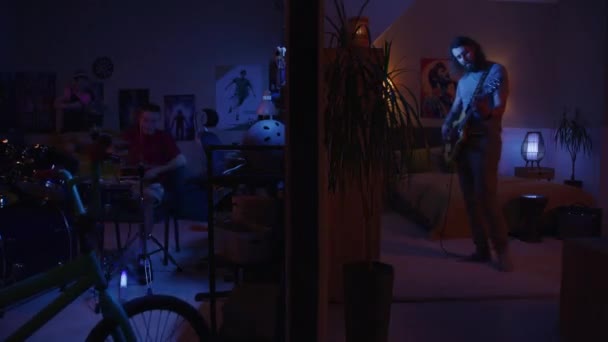 夜はエレキギター 少年少女はドラム ウクレレをアパートで弾き 光がちらつきます 壁で区切られた2つの部屋のビュー エンターテイメント 街のコンセプト — ストック動画