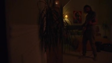 Adam yanıp sönen ışıklarla yatak odasında elektro gitar çalıyor. Kamera görüş açısını değiştiriyor. Yan evde oturan genç kız ve erkek, davul ve ukulele çalıyor. Duvarla ayrılmış iki oda. Komşuluk kavramı.