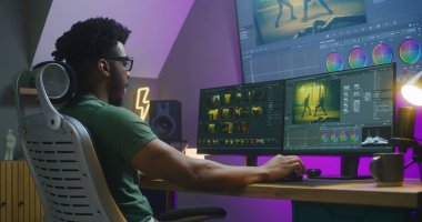Afrikalı Amerikalı video yapımcısı aksiyon filmi düzenliyor, renk değerlendirmesi yapıyor, evde çalışıyor. Bilgisayar ve büyük dijital ekranda RGB araçları ve tekerlekleriyle yazılım arayüzü. Film sonrası prodüksiyon kavramı.