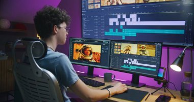 Genç editör, video yapımcısı, astronotlarla film düzenliyor, ev ofisinde çalışıyor. Bilgisayar ve büyük dijital ekrandaki alet ve ses parçalarıyla film görüntüleri ve program arayüzü. Yapım konsepti.