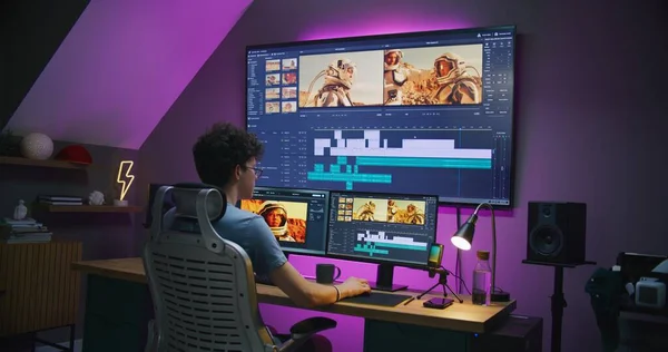 Young editor, video maker edits movie with astronauts, works at home office. Film footage and program interface with tools and sound tracks on computer and big digital screen. Post production concept.