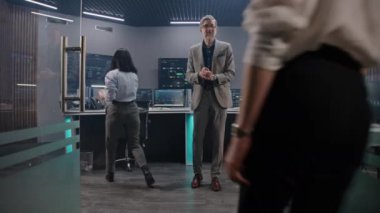 Olgun veri bilimci, bilişim mühendislerini izleme odasında karşılıyor. Destek uzmanları bilgisayarların başında oturup gerçek zamanlı analiz çizelgelerini kontrol ediyorlar. Engelleme ağı olan birden fazla büyük ekran. Dolly vurdu..