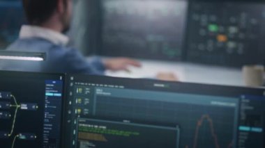 Profesyonel yazılım programcısı bilgisayarın önünde oturur, izleme odasındaki büyük veri sunucusunu izler. Kamera gerçek zamanlı analiz çizelgeleriyle bilgisayar ekranına giriyor. Siber güvenlik kavramı.