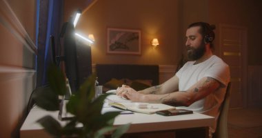 Konsantre mali analist ya da elinde kalemle klavye yazan tüccar ve notlar alıyor. LED lambalarla aydınlatılmış masa. Ev konseptinde çalışmak.