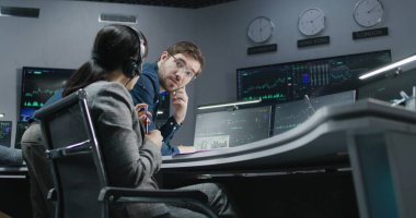 Finansal analistler bilgisayarda gerçek zamanlı hisse senedi verilerini izleyip tartışıyorlar. İş adamları banka ofisinde çalışır. Döviz piyasası haritaları olan büyük dijital ekranlar. Kripto para birimi ticareti ve analizi.