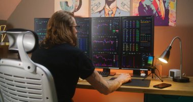 Konsantre tüccarlar gerçek zamanlı hisse senedi, çoklu monitörlü bilgisayar çalışma istasyonunda borsa grafikleri, klavyedeki tipler. Adam merkez büroda uzaktan yatırım işinde çalışıyor. Kripto para ticareti.