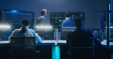 Bilgi işlem uzmanları ve yazılım programcılarından oluşan çok ırklı bir ekip, veri sunucusu, analiz çizelgeleri ve bilgisayarlardaki engelleme ağı ve geceleri izleme ofisindeki büyük dijital ekranlar üzerinde çalışıyor..