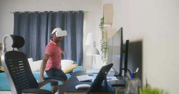 アフリカ系アメリカ人のゲーマーは Vrヘッドセットを使用して拡張現実ゲームでサーフィンに乗る 幸せな男は家で余暇を過ごす モダンなデザインの客室 日常生活の中でハイテク機器を使うという概念 — ストック写真