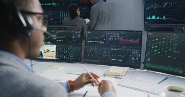 金融分析小组在多个大银幕上分析外汇市场图表 向在电脑上工作的非裔美国人开枪射击 他们拥有实时股票 贸易和投资 — 图库照片