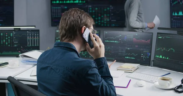 男经纪人通过电话交谈 在银行办公室工作 用实时股票在多台监控电脑上工作 交换市场图表 有数据的大数字屏幕 加密货币交易和分析 — 图库照片