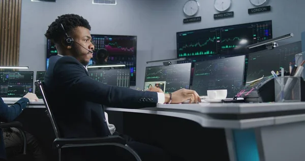 非裔美国商人在电脑上做笔记和工作 并展示实时股票 同事们在大屏风的背景下分析外汇市场图表 加密货币交易和投资 — 图库照片