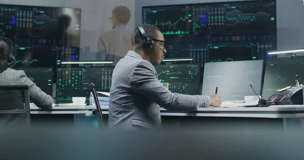 非裔美国人金融分析师监测计算机上的实时股票 用笔写数据 在银行办公室工作 大型数字显示屏上显示的外汇市场图表 投资或分析 — 图库照片