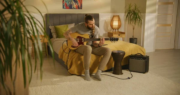 男は寝室でギターを弾く — ストック写真