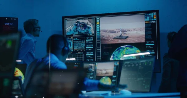 stock image Flight control operators monitor space mission on computers in command center, have communication with astronaut. Team watch successful space rocket launch on big digital screen. Space exploration.