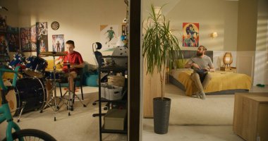 Genç çocuk yatak odasında davul çalar. Erkek müzisyen evde geleneksel djembe davul çalıyor. Duvarla ayrılmış iki oda ya da dairenin görüntüsü. Düşük seviyede ses yalıtımı. Mahalle kavramı.