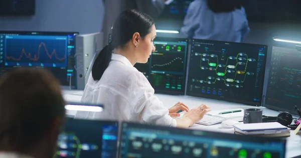 在现代监控控制室 女性It技术专家在拥有数据服务器和区块链网络数据库的计算机上工作 背景上的软件工程师团队和大型数字屏幕 — 图库照片