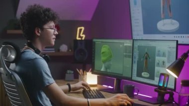 Genç 3D tasarımcı video oyunu geliştirir, karakter veya giysi oluşturur, PC üzerinde evden uzaktan çalışır ve profesyonel yazılım arayüzü ve 3D modelleme ve tasarım araçları ile büyük dijital ekranda çalışır.