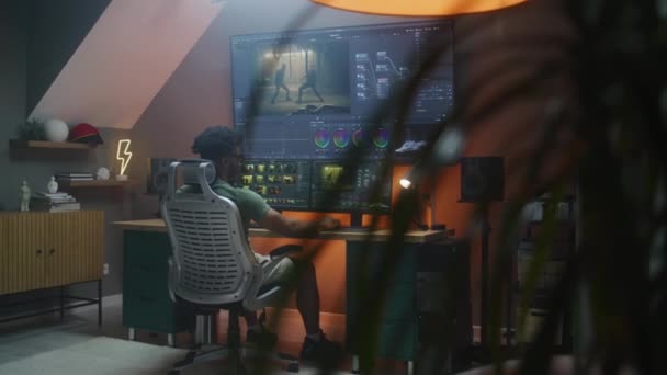 非裔美国男性编辑做色彩分级 在总部工作 多显示器计算机和大数字屏幕上的动作片段和程序接口 电影后期制作的概念 — 图库视频影像