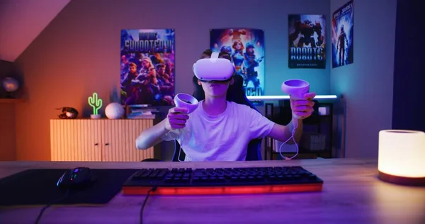 Vrヘッドセットの若いゲーマーは ワイヤレスコントローラを使用して仮想現実オンラインビデオゲームをプレイします スタイリッシュなネオンルームで余暇を楽しんでいる男の子 自宅でゲーム Pc画面の視点からの眺め — ストック写真