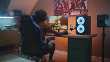 Profesyonel eSports Afro-Amerikalı, kulaklıklı genç oyuncu modern bilgisayarda, şık bir odada üçüncü şahıs 3D nişancı oynuyor. Video oyunu canlı yayın ya da siber spor yarışması. Evde oyun oynamak..