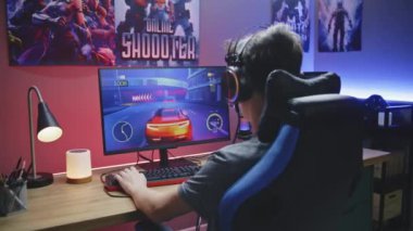 Genç oyuncu evdeki PC 'de araba yarışı simülatöründe oynuyor. Bilgisayar monitörü çevrimiçi video oyunu canlı yayını ya da siber spor şampiyonluğu. Masa, RGB LED lambasıyla aydınlatılmış. Dolly vurdu..
