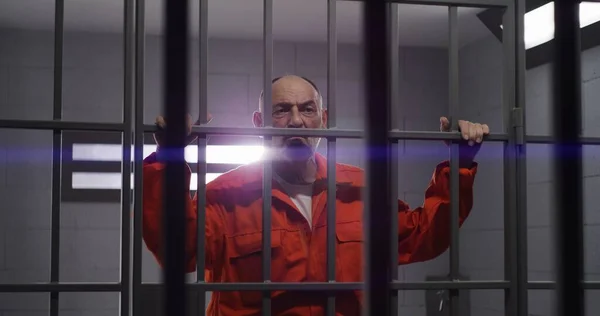 Elderly Prisoner Orange Uniform Holds Hands Metal Bars Criminal Serves — Stock Photo, Image