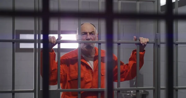 Elderly Prisoner Orange Uniform Holds Hands Metal Bars Criminal Serves — Stock Photo, Image