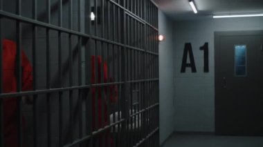 Turuncu üniformalı mahkumlar hapishane hücrelerinde yürürler, metal parmaklıklar tutarlar. Suçlu suçlular, suçtan hapis cezasına çarptırıldılar. Hapisteki, ıslahevindeki ya da ıslahevindeki mahkumlar. Adalet sistemi.