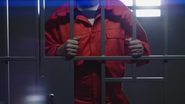 Elderly Prisoner Orange Uniform Holds Metal Bars Stands Prison Cell — Stock Video