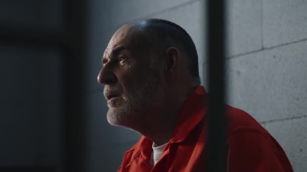Ηλικιωμένος Εγκληματίας Πορτοκαλί Στολή Κάθεται Στο Κρεβάτι Της Φυλακής Και — Αρχείο Βίντεο