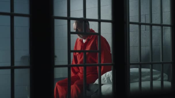 Starší Zločinec Oranžové Uniformě Sedí Vězeňské Posteli Myslí Svobodu Vězeň — Stock video
