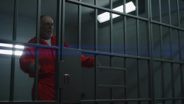 Starší Zločinec Oranžové Uniformě Podívá Zamřížované Okno Opře Mříže Vězeňské — Stock video