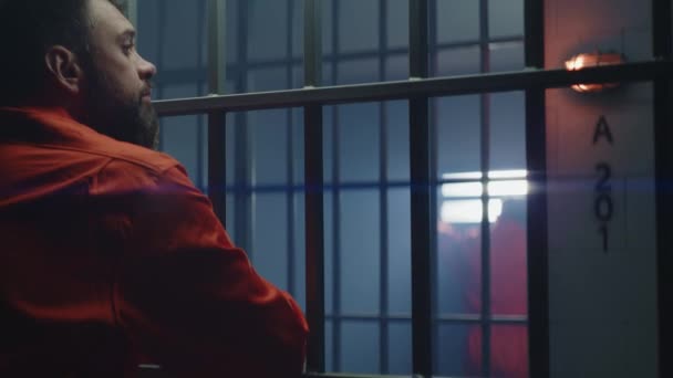 Mannen Orange Uniform Står Fängelsecell Och Håller Hand Barer Grannfången — Stockvideo